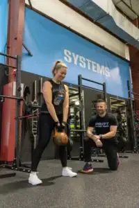 Female client lifting weights under the guidance of a personal trainer